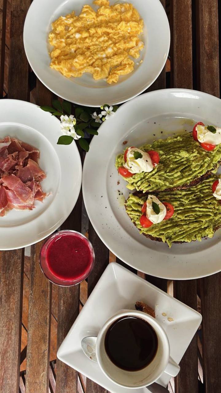 Brunch com ovos mexidos, pesto pasta, presunto, suco de beterraba e café em mesa rústica